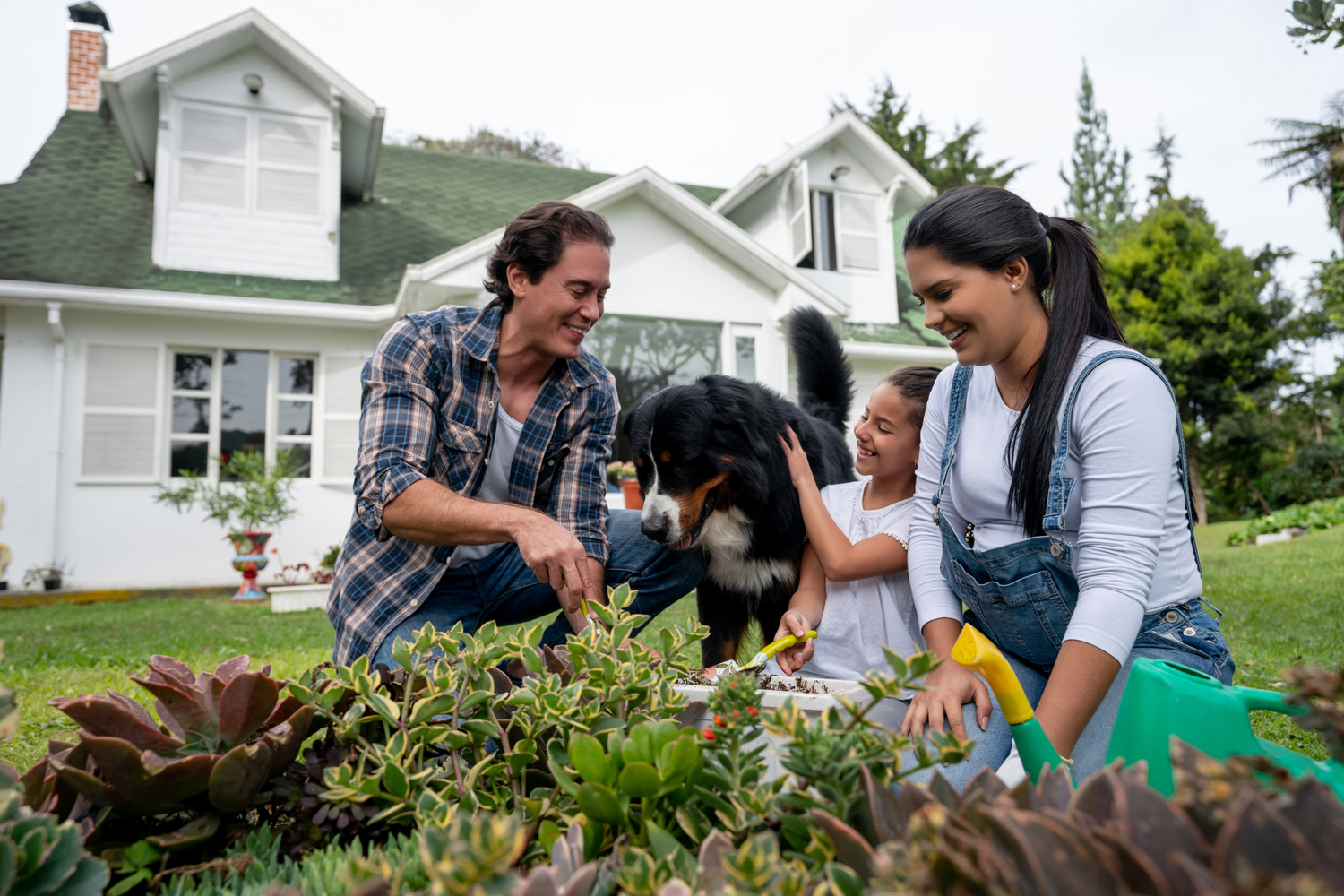 Family with a dog gardening in front of a house